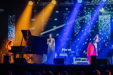 Valmiera, Letonya - 29 Aralık 2025: Yamaha. Şarkıcı sahnedeki seyirciyi piyano, canlı ışıklar ve dinamik performansla cezbederek büyüleyici bir atmosfer yaratıyor.