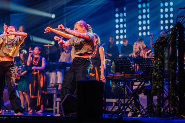 Valmiera, Letonya - 29 Aralık 2025: Yamaha. Dansçılar sahnede canlı performans sergiliyorlar. Renkli ışıklar ve coşkulu seyirciler arka planda heyecan yaratıyorlar.