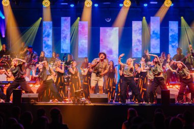 Valmiera, Letonya - 29 Aralık 2025: Yamaha. Göstericiler sahnede renkli ışıklar ve onları çevreleyen canlı bir atmosferle dinamik dans hareketleri sergiliyorlar.