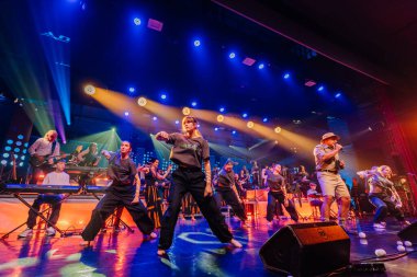 Valmiera, Letonya - 29 Aralık 2025: Yamaha. Sahnede enerjik bir atmosfer yaratmak için canlı ışıklar eşliğinde dinamik şarkı söyleyip dans eden yetenekli müzisyenlerden oluşan bir grup.