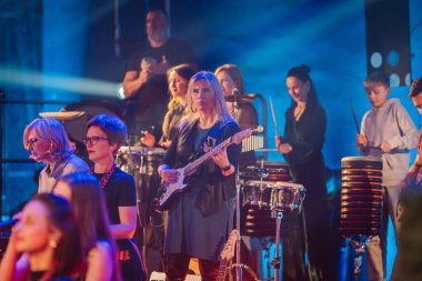 Valmiera, Letonya - 29 Aralık 2025: Yamaha. Sahnede enstrüman çalan bir grup bayan müzisyen canlı bir konserde enerjik bir atmosfer yaratıyor.