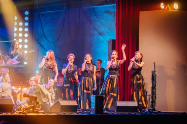 Valmiera, Letonya - 29 Aralık 2025: Yamaha. Kadın vokalistler canlı bir atmosfer yaratmak için renkli ışıklar ve canlı kostümlerle sahnede enerjik bir performans sergiliyorlar.