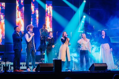 Valmiera, Letonya - 29 Aralık 2025: Yamaha. Şarkıcılar canlı bir konser sırasında seyirciyi canlı ışıklar ve duman efektleriyle büyülüyor.