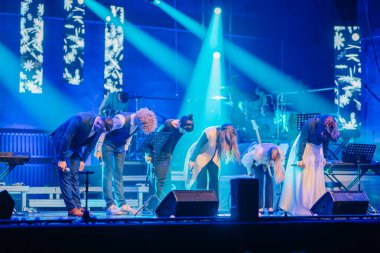 Valmiera, Letonya - 29 Aralık 2025: Yamaha. Müzisyenler, parlak mavi ışıklarla, enerjik bir performansın ardından sahnede baş eğerek dinamik bir ortam yaratıyorlar.