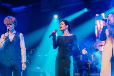 Valmiera, Letonya - 29 Aralık 2025: Yamaha. Beyaz tenli sanatçılar renkli ışıklar ve dumanla sahnede coşkuyla şarkı söylüyor. Konser ortamını canlandırıyorlar.