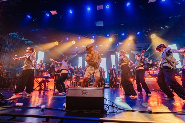 Valmiera, Letonya - 29 Aralık 2025: Yamaha. Erkek dansçı, renkli ışıklar ve cazip bir atmosfer yaratan müzisyenlerle sahnede dinamik hareketler sergiliyor