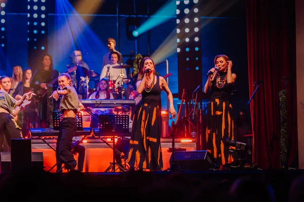 Valmiera, Letonya - 29 Aralık 2025: Yamaha. Kadın vokalistler, renkli ışıklar ve heyecan verici bir atmosfer yaratan canlı müzik grubuyla sahnede enerjik bir performans sergiliyorlar.