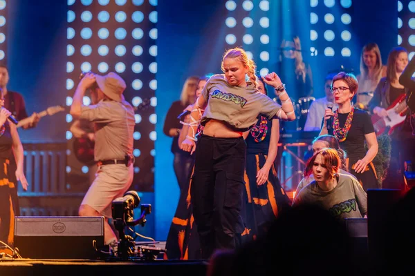 Valmiera, Letonya - 29 Aralık 2025: Yamaha. İki genç kadın renkli ışıklar ve coşkulu kalabalıkla dolu canlı bir müzik festivalinde sahnede enerjik bir şekilde dans ediyorlar.