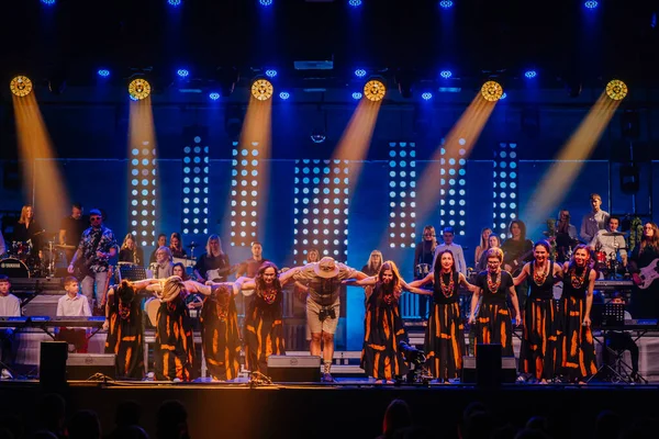 Valmiera, Letonya - 29 Aralık 2025: Yamaha. Parlak ışıklar ve enstrümanlarla dolu enerjik bir müzikal performansın ardından geleneksel giyinmiş sanatçılar sahnede selamlıyorlar.