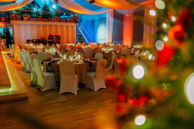 Kutlama için şölen salonu seti, beyaz sandalyeli zarif masalar, sıcak ortam ışıkları, ve tatil etkinlikleri için mükemmel neşeli bir atmosfer.