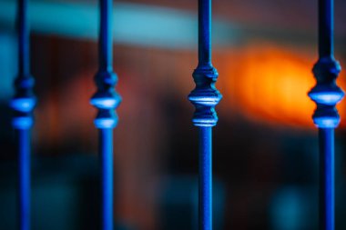 Dekoratif metal çubuklarda karmaşık tasarımlar ve bulanık ve sıcak bir arkaplan üzerine kurulmuş mavi bir renk, çarpıcı bir görsel karşıtlık ve ortam yaratır.