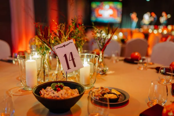 Siyah bir kâse salata, mum ve dekoratif aksanla güzel düzenlenmiş yemek masası festival havasını yükseltiyor ya da kutlama yapıyor.