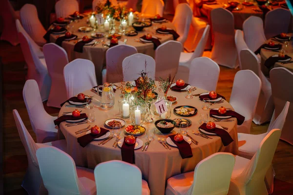 Yuvarlak masa zarif bir şekilde dekoratif tabaklar, mumlar ve çiçek süslemeleriyle yemek ve kutlama için ortam yaratıyor.