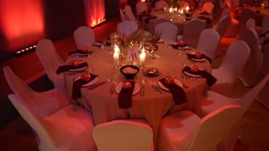 Çok güzel düzenlenmiş bir yemek masasında zarif sofra takımı ve süslemeler sergileniyor. Yumuşak ışıklandırmayla aydınlatılıyor. Misafirleri unutulmaz bir yemek deneyimi yaşamaları ve eğlenmeleri için davet ediliyor.