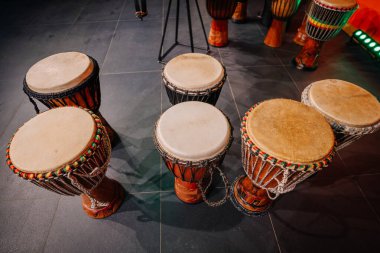Geleneksel davullar, parlak bir müzikal atmosferde işçiliklerini ve kültürel önemlerini vurgulayan koyu kartonlu bir zeminde güzelce düzenlenmiştir.