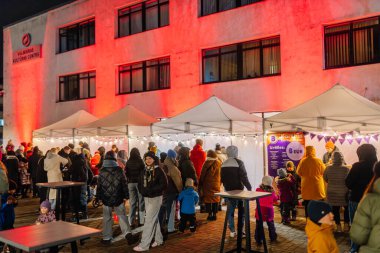 Valmiera, Letonya - 30 Kasım 2025: Akşamları neşeli ışıklar, çadırlar ve hareketli bir atmosfer seven insanlarla dolu bir açık hava pazarı