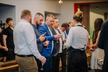 Sigulda, Letonya - 05 Aralık 2025: Şirket galası. Erkekler ve kadınlar kapalı mekanlarda sosyalleşirken içkinin tadını çıkarıyorlar.