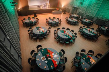 Sigulda, Letonya - 05 Aralık 2025: Şirket galası. Etkinlikler için hazırlanmış geniş bir ziyafet salonunda şenlikli süslerle süslenmiş yuvarlak masalar.