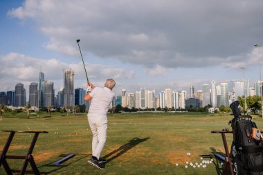 Dubai, Birleşik Arap Emirlikleri - 17 Ocak 2026: Beyazlar içindeki golfçü Dubai 'de bir golf sahasında sallanıyor.