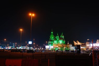 Dubai, Birleşik Arap Emirlikleri - 13 Ocak 2026: Dubai 'deki aydınlık yeşil binaların gece görüşü, hareketli bir şehir ortamında süslü tasarımlar ve parlak ışıklar yer alıyor