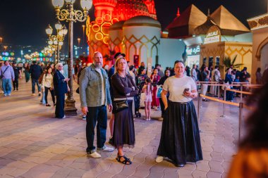 Dubai, Birleşik Arap Emirlikleri - 13 Ocak 2026: Dubai 'de gece yarısı aydınlık yapılar önünde üç kişi poz verirken, kalabalık bir kalabalık da yakınlarda