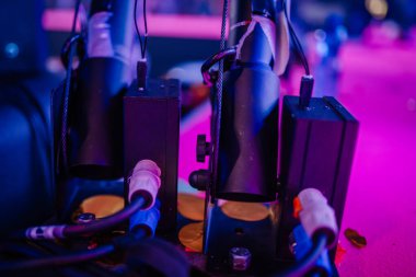 Bağlı kablolar ve kontrol kutularından oluşan CO2 konfeti topu kurulumu, arkaplanda renkli ışıklandırma efektleri bulunan bir sahnede