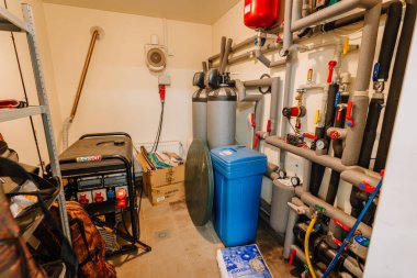 Kuldiga, Letonya - 30 Ocak 2026: Konut ortamında raflarda depolanan su filtreleme sistemi, jeneratör ve çeşitli araçlara sahip kamu hizmetleri odası