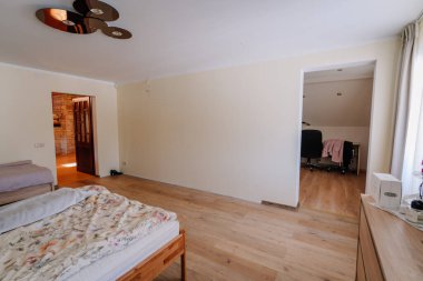 Kuldiga, Letonya - 30 Ocak 2026: Ahşap zeminli modern yatak odası, yataklı iki yatak ve açık kapılı bir çalışma alanı