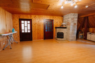 Kuldiga, Letonya - 30 Ocak 2026: Taş şömineli ahşap kulübe oturma odası, iki koyu ahşap kapı ve köşede bir ütü masası