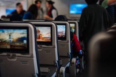 Dubai, Birleşik Arap Emirlikleri - 18 Ocak 2026: Arka planda bir şehir manzarası ve bulanık figürleri gösteren yolcu koltuklu uçak kabini