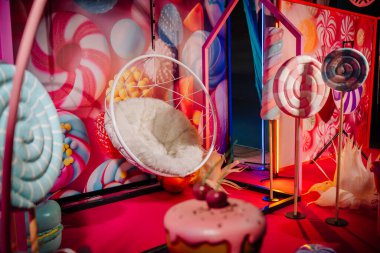 Büyük lolipopları olan şeker temalı bir dekor, rahat bir sallanan sandalye ve parlak renkler eğlenceli bir iç mekanda tuhaf bir atmosfer yaratır.