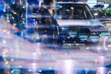 Riga, Letonya - 4 Şubat 2026: Chery. Chery TIGGO 9 aracı, bulanık figürler ve renkli yansımalarla bir marka tanıtım etkinliğinde sergilendi