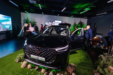 Riga, Letonya - 4 Şubat 2026: Chery. Chery TIGGO B SUV, çağdaş bir alanda yeşil ve dijital ekranlarla çevrili bir marka tanıtım etkinliğinde sergilendi