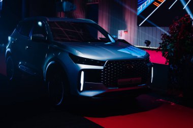 Riga, Letonya - 4 Şubat 2026: Chery. Chery TIGGO SUV canlı ışıklandırma ve çağdaş ışıklandırma teknolojisiyle bir otomotiv sunumunda sergilendi