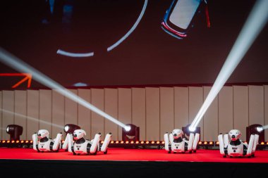 Riga, Letonya - 4 Şubat 2026: Chery. Kiraz rengi TIGGO robotik modelleri kırmızı halı sahnesinde parlak ışıklandırma ve büyük ekran arkaplanı ile gösteriliyor