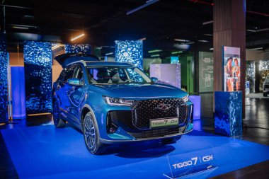 Riga, Letonya - 4 Şubat 2026: Chery. Chery TIGGO 7 CSH modeli, mavi ışıklandırma ve promosyon unsurlarının yer aldığı çağdaş bir sergi salonunda sergilendi