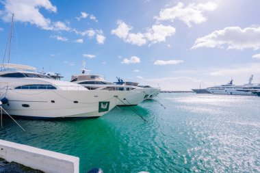 Marbella, İspanya - 13 Şubat 2026: Lüks yatlar turkuvaz suyu ve berrak bir gökyüzü ile bir marinaya demirlediler ve güzel bir kıyı manzarası yarattılar