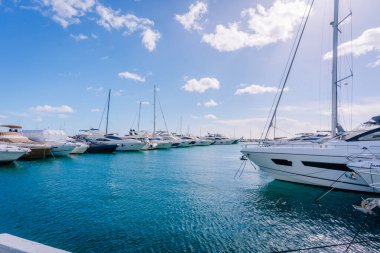 Marbella, İspanya - 13 Şubat 2026: Lüks yatlar turkuvaz suyu ve parlak bir gökyüzü ile bir marinaya demirlenmiş, güzel bir kıyı manzarası yaratıyor.