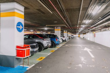 Marbella, İspanya - 13 Şubat 2026: İyi ışıklandırılmış bir çevrede park halindeki çok sayıda park yeri, yön işareti ve yapısal sütunların yer aldığı yer altı otoparkı