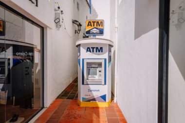 Marbella, İspanya - 13 Şubat 2026: Beyaz duvarlı ve döşemeli dar bir sokakta bulunan ATM makinesi, Euronet markasını belirgin bir şekilde gösteriyor
