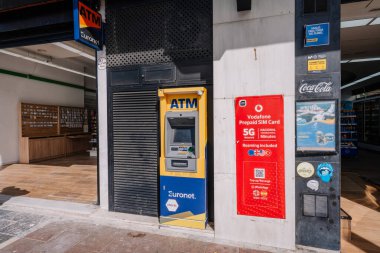 Marbella, İspanya - 13 Mart 2026: Vodafone ön ödemeli SIM kart reklamı ve Coca-Cola markasının yer aldığı bir perakende mağazasının önünde Euronet ATM pozisyonu