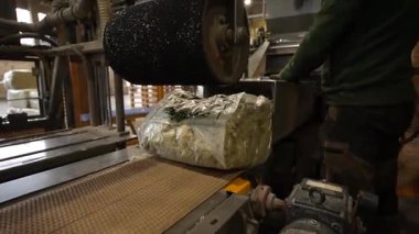 Cesis, Letonya - 21 Kasım 2025: Yeşil gömlekli işçi, geri dönüşümlü kağıdı bir üretim tesisinde selüloz yalıtım makinesine dönüştürüyor