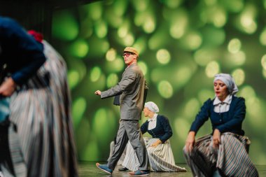 Valmiera, Letonya - 27 Aralık 2025 Letonya Halk Dansı Konseri. Letonyalı halk dansları gösterisi dansçıları geleneksel kıyafetlerle sergiliyor ve arka planda yeşil ışık var.