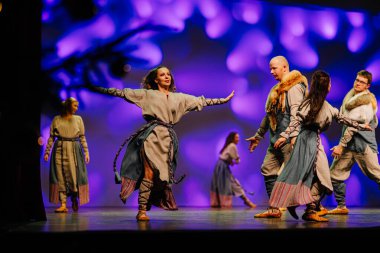 Valmiera, Letonya - 27 Aralık 2025 Letonya Halk Dansı Konseri. Letonyalı halk dansçıları sahnede canlı ışıklandırma ve kostümlerle geleneksel dans figürlerini sergilediler