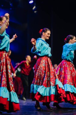 Valmiera, Letonya - 27 Aralık 2025 Letonya Halk Dansı Konseri. Letonyalı halk dansçıları sahnede renkli kostümlerle geleneksel kıyafet ve enerjik hareketler sergiliyor