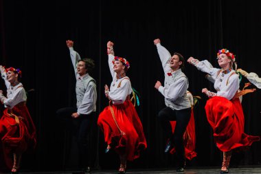 Valmiera, Letonya - 27 Aralık 2025 Letonya Halk Dansı Konseri. Geleneksel giyinmiş Letonyalı halk dansçıları yeteneklerini sahnede gösteriyorlar. Parlak kostümler ve dinamik pozlarla.