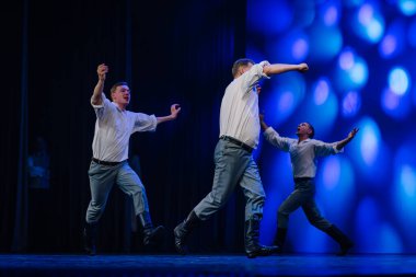 Valmiera, Letonya - 27 Aralık 2025 Letonya Halk Dansı Konseri. Geleneksel giyinmiş Letonyalı halk dansçıları sahnede canlı ışıklandırma efektleriyle performans sergiliyorlar.