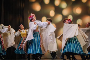 Valmiera, Letonya - 27 Aralık 2025 Letonya Halk Dansı Konseri. Geleneksel kıyafetli dansçılar yeteneklerini sahnede canlı ışıklandırma ve şenlikli dekorasyonlarla sergiliyorlar.