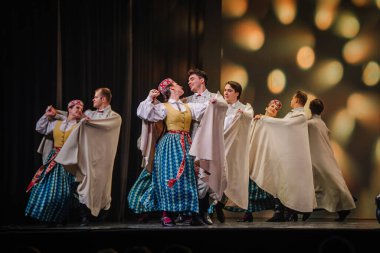 Valmiera, Letonya - 27 Aralık 2025 Letonya Halk Dansı Konseri. Geleneksel kıyafetli dansçılar canlı ışıklandırma ve anlamlı hareketlerle performanslarını sahnede sergilerler.