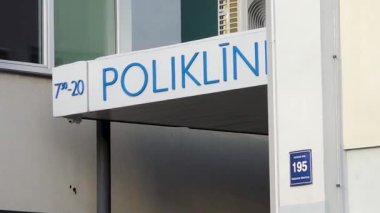 Valmiera, Letonya - 14 Şubat 2026: Poliklinika tabelası bir klinik binasında belirgin bir şekilde sergilendi, kentin giriş ve mimari özelliklerini vurguladı